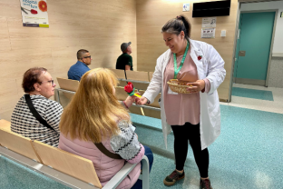 Una voluntària entregant una rosa manual a una pacient