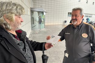 Un miembro del equipo de seguridad entregando uno de los dípticos informativos a un paciente